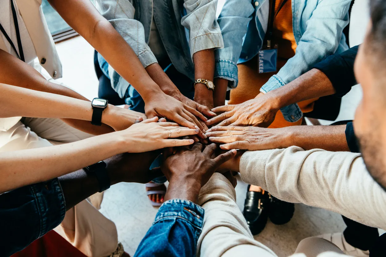 Hände eines Teams übereinander als Zeichen der Zusammenarbeit